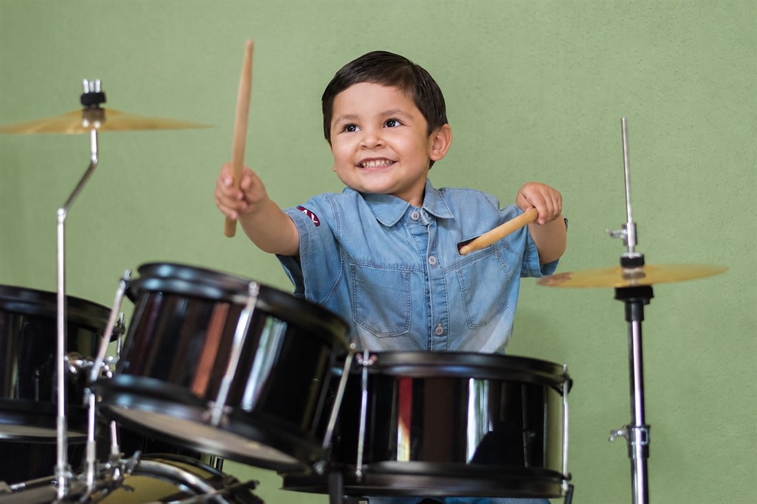 Young student smiling while playing drums